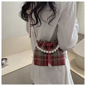 Detail of red plaid bucket bag with pearl handle and metal chain strap in high-end finish