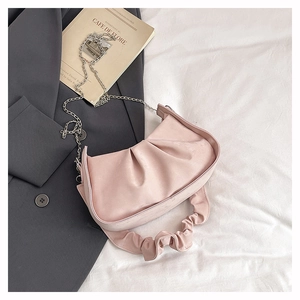 Pink pleated dumpling bag detail with silver chain strap on a stylish background