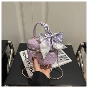 Detail of lavender quilted vanity bag with metal chain strap and silk scarf bow handle