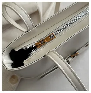 Detailed macro view of the premium bronze metal zipper on a white leather tote bag
