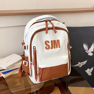 Minimalist white and brown contrast canvas backpack with SJM letter design on glass table