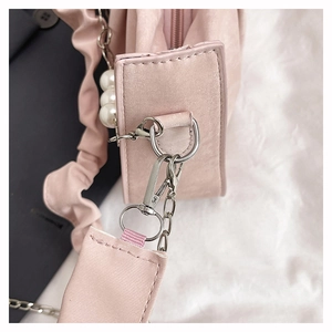 Detail of pink shoulder bag showing metal hooks, beaded chain, and pleated fabric strap