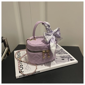 Detail of purple quilted mini bucket bag with silk scarf bow and gold chain strap