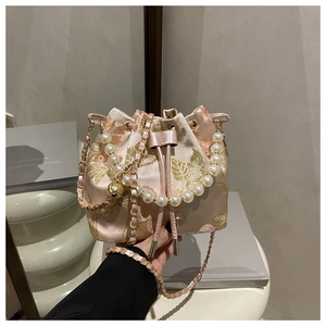 Detail of pink satin bucket bag with gold floral embroidery and pearl handle