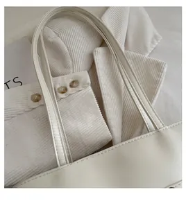 Detailed view of cream leather tote bag with flat handle and soft corduroy texture