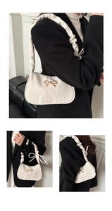 Détail du sac sous le bras à motif marbre blanc avec nœud doré et bandoulière froncée