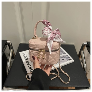Detail of pink quilted bucket bag with silk scarf handle and golden chain strap