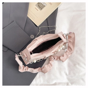 Detail of pink satin handbag with pleated strap and pearl metal clover chain