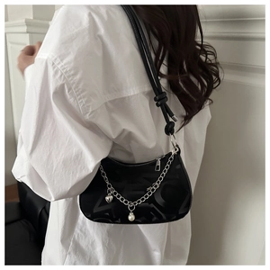 Detail of black jacquard moon bag with silver chain heart and pearl charms on model