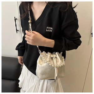 Detail of cream silk bucket bag with pearl handle and elegant floral embroidery