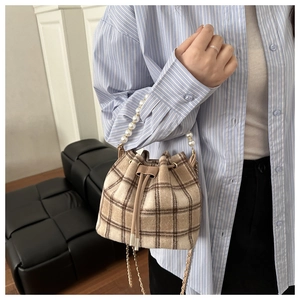 Detail of vintage plaid bucket bag with pearl handle and metal chain shoulder strap