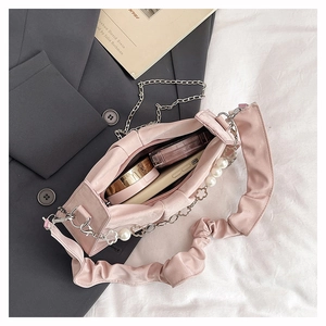 Detail of pink pleated crossbody bag interior with pearl charms and metal chain strap