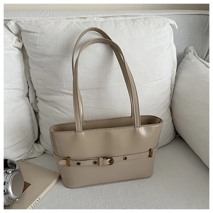Détail du sac cabas en cuir PU kaki avec boucle métallique sur un canapé blanc chic