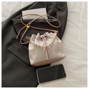 Detail of pink jacquard bucket bag with pearl handle and elegant floral patterns
