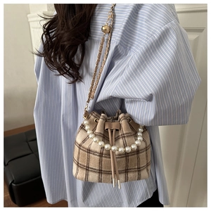 Detail of plaid wool bucket bag with pearl handle and golden ball chain strap