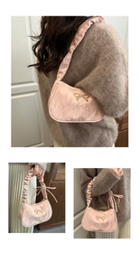 Détail d'un sac à bandoulière plissé rose avec boucle nœud doré et texture satin