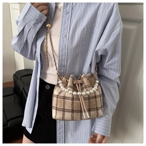 Detail of checkered bucket bag featuring pearl handle and drawstring closure