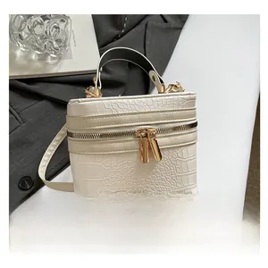 Detail of cream crocodile embossed box bag featuring gold hardware and a top handle