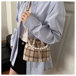 Close-up of vintage plaid bucket bag with pearl handle and metal chain strap