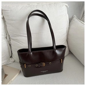 Détail d'un cabas en cuir marron foncé avec boucle dorée et sangle réglable