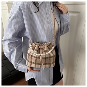 Detail of British style checkered bucket bag featuring pearl handle and chain strap