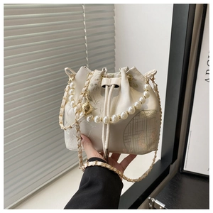 Detailed close-up of cream floral bucket bag with pearl handle and golden chain strap