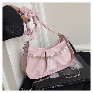 Detail of pink pleated handbag with pearl flower chain and ruched handle on book