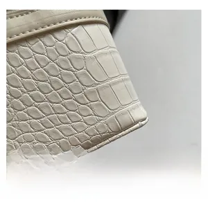 Close-up of beige crocodile pattern texture and neat stitching on a square handbag