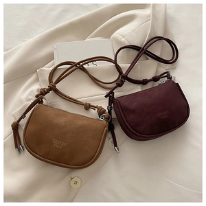 Close-up of brown and burgundy saddle bags with knot straps on minimalist blazer