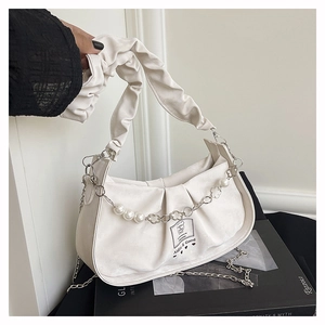 Detail view of a white pleated handbag with pearl handle and bear print on art books