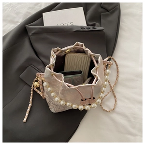 Macro view of pink jacquard bucket bag showing spacious interior with pearl and chain straps