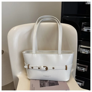 Close-up of white faux leather tote bag with gold buckle on a stylish chair