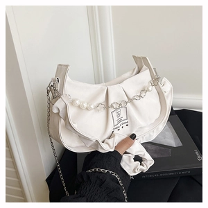 Detail of white pleated handbag featuring large pearls and silver floral chain decoration
