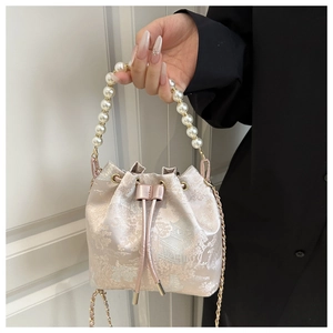 Detailed view of champagne bucket bag with Chinese embroidery and pearl handle strap