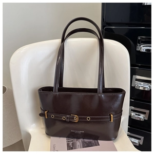 Detail of dark brown leather tote bag with gold buckle and embossed logo text