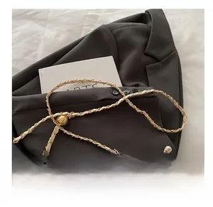 Detailed macro view of the pearl handle and embroidered texture on an ivory bucket bag