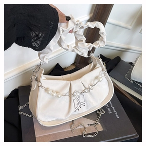 Detail of white pleated cloud bag featuring large pearls and hollow metal flower chain