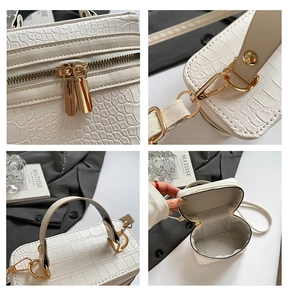 Detail view of white crocodile pattern handbag featuring gold zippers and hardware