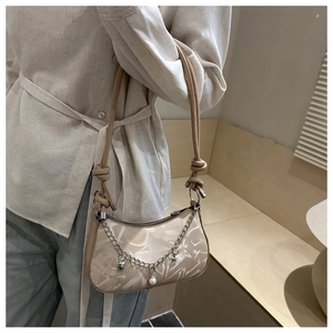 Close-up of cream chain underarm bag with decorative pearls and knotted strap detail