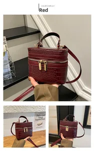 Detail view of red crocodile-embossed mini box bag with gold zipper and top handle