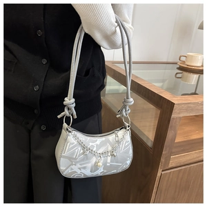 Detail showing silver crescent shoulder bag with metallic chain and pearl heart charms