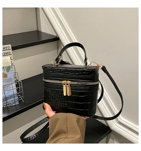 Close-up of black crocodile embossed box bag with gold dual zippers and top handle