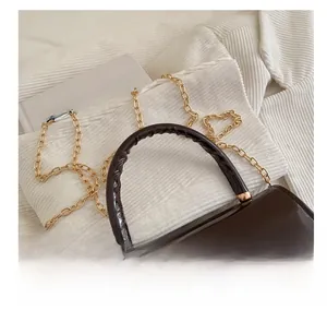 Macro shot of brown patent leather bag with gold chain strap and ruched handle detail