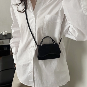 Minimalist black small square crossbody bag with top handle and curved flap design