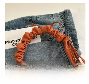 Detail of caramel pleated bag showing soft scrunched handle and matte fabric texture