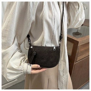 Detail of a dark brown half-moon crossbody bag with a matte finish and knotted rope strap