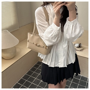 Detail of beige underarm bag featuring decorative strap with metallic buckle