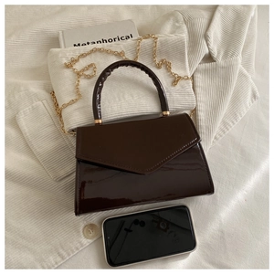 Detail of dark brown patent leather mini bag with gold chain and phone for size comparison