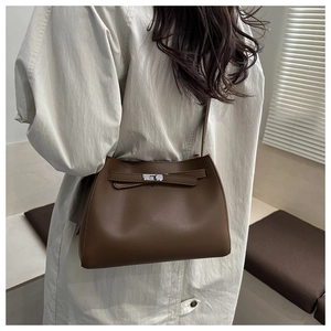 Bolso estilo Kelly marrón mostrado con una modelo con una gabardina beige elegante