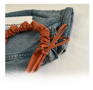 Close-up of caramel pleated shoulder bag with scrunchie strap and knot detail